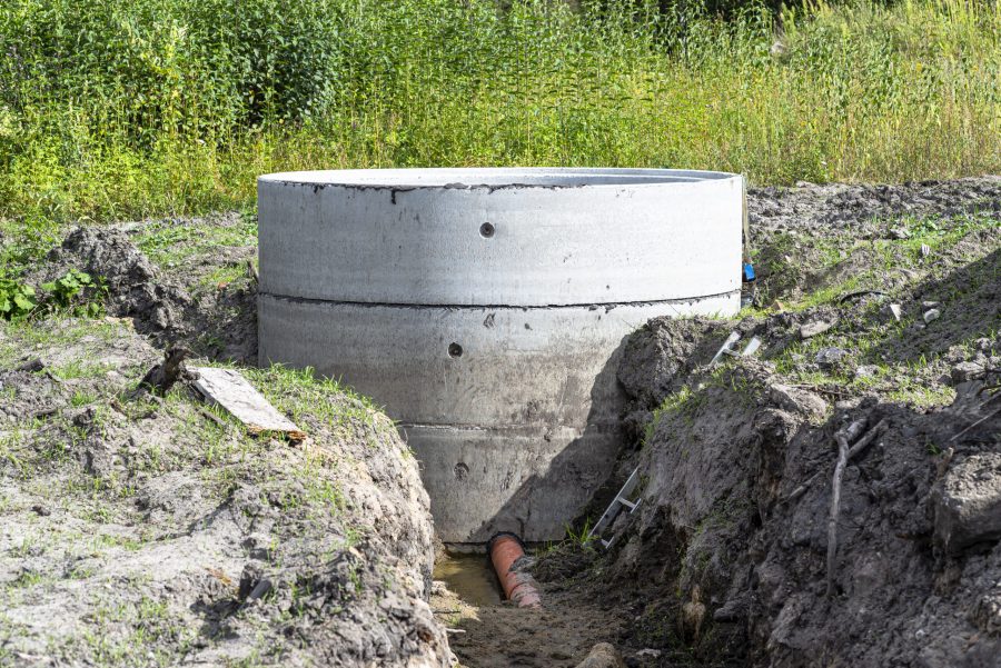 Concrete well ring with exposed pipe in muddy field